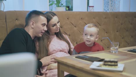 pregnant lady sits between handsome husband and toddler son