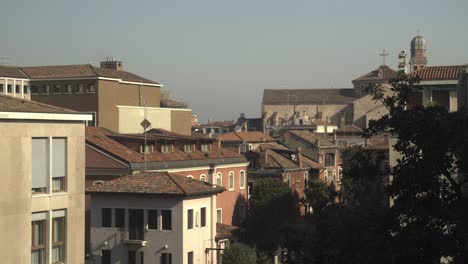 a wide shot slowly zooms out, revealing a panorama of traditional venetian rooftops and a historic cityscape under a clear sky.