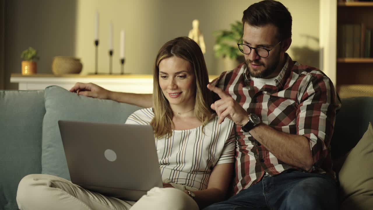 una pareja usando una computadora portátil en el sofá.