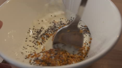 mezclar cereales con yogur y semillas de chía en un bol usando una cuchara - cierre, cámara lenta