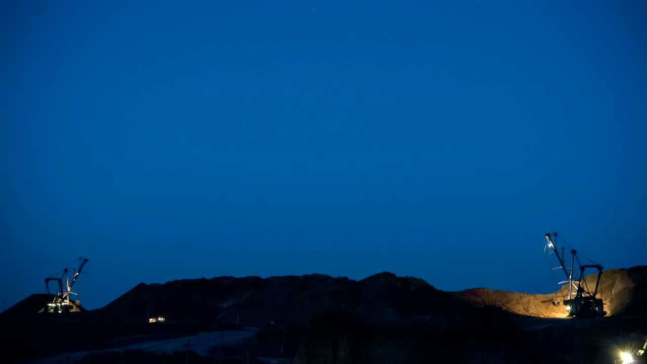 Time lapse of excavators loading ore into dump-trucks at the sunset.