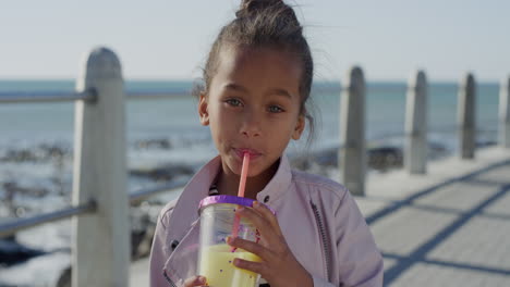 retrato de una niña hermosa bebiendo jugo sonriendo feliz disfrutando de unas cálidas vacaciones de verano en la playa