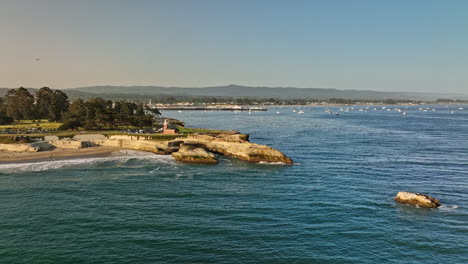 Santa-Cruz-California-Antena-V1-Vuela-Alrededor-Del-Punto-Del-Faro-Y-Sella-La-Roca-Con-Olas-Rompiendo-En-La-Orilla,-La-Vista-Panorámica-Revela-Un-Sol-Brillante-En-El-Cielo-Al-Atardecer---Filmado-Con-Cine-Mavic-3---Mayo-De-2022