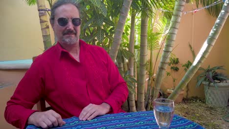 closeup of mature man wearing guayabera shirt looks directly at camera