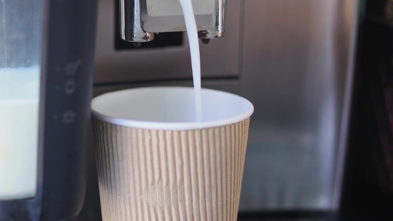 Latte erogato in un bicchiere di carta da una macchina da caffè automatica