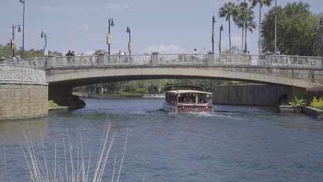 A-passenger-boat-travels-underneath-a-busy-bridge-full-of-people