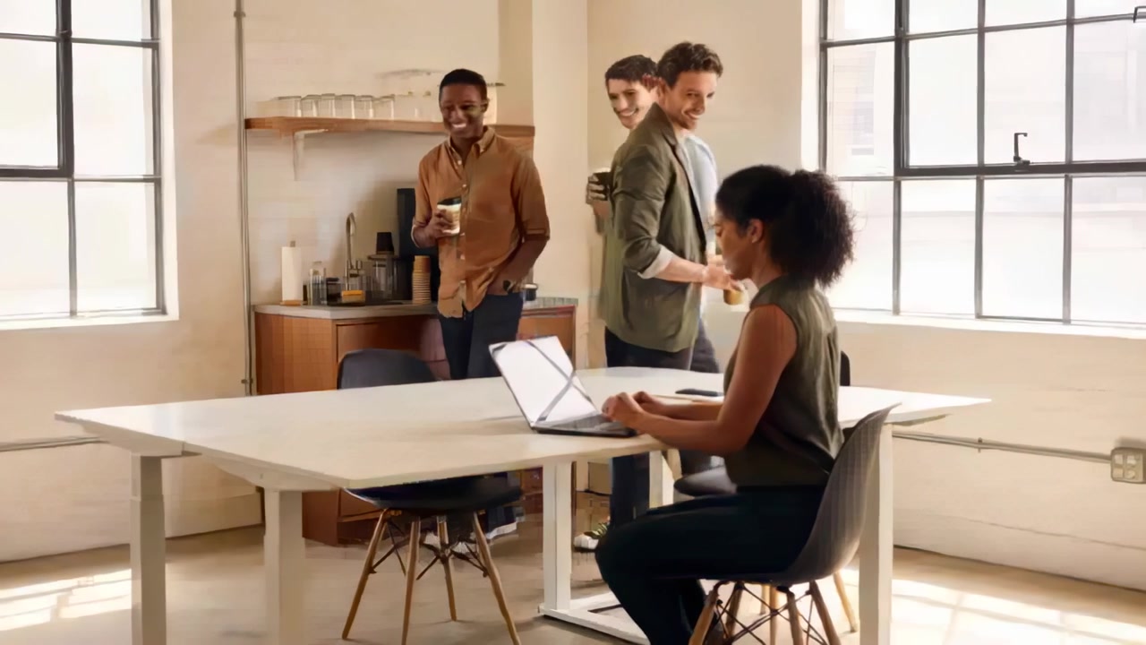 Leaving counter team holding cups greeting woman in olive top at kitchen table laptop, copy space