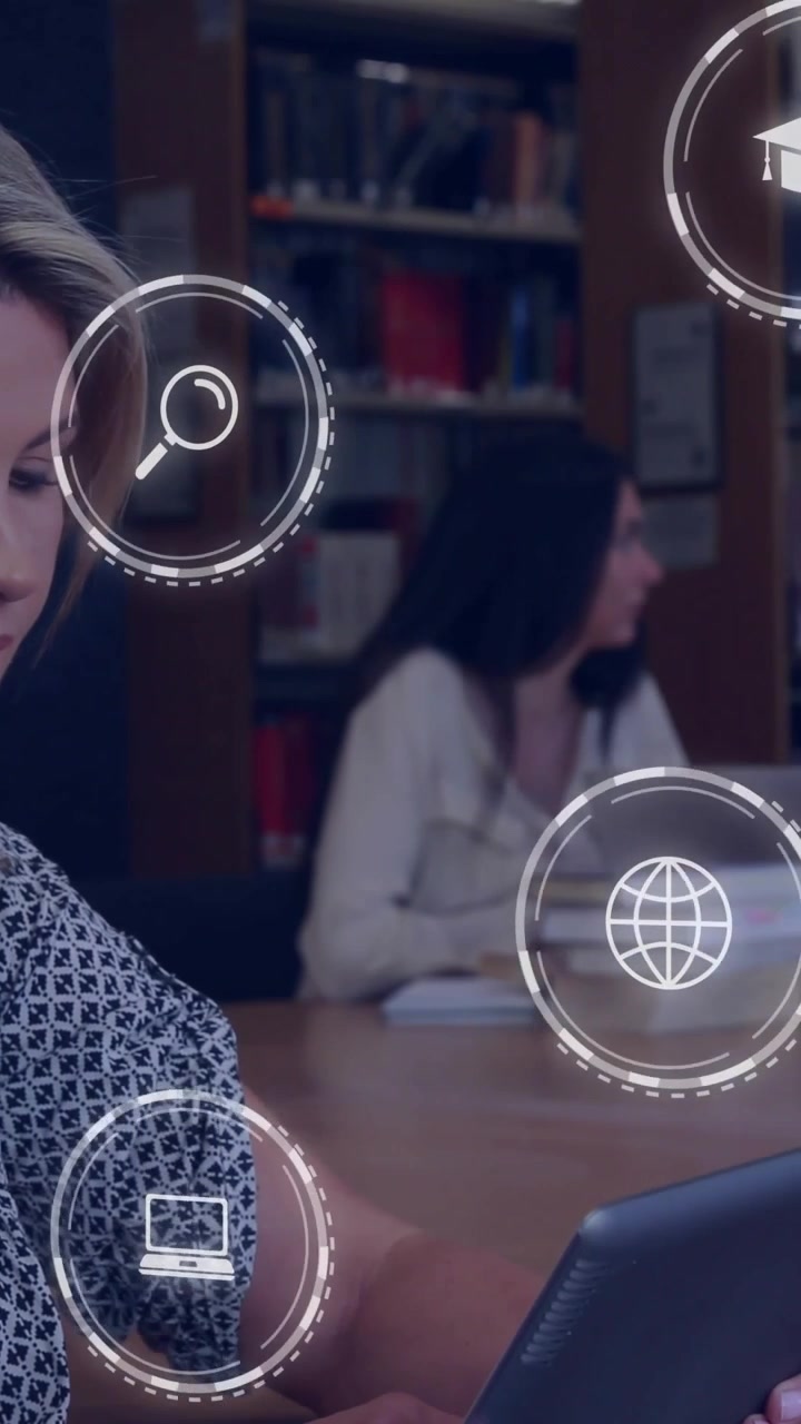 Video verticale: Donna che usa un tablet in biblioteca, toccando lo schermo genera icone di studio sopra un laptop e dei libri.