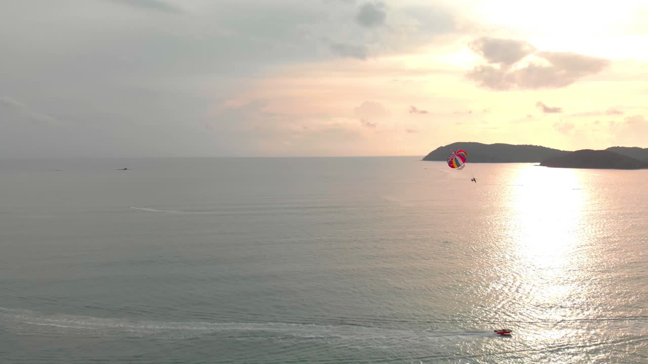 Panorâmica lenta mostrando um praticante de parasailing em Langkawi