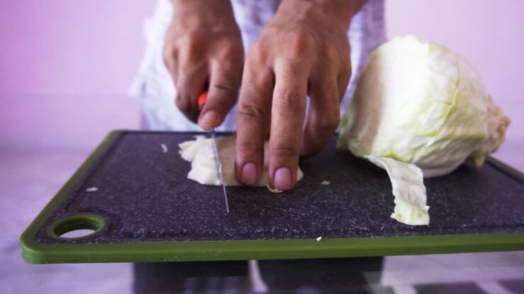 Giovane uomo che taglia il cavolo per l'insalata