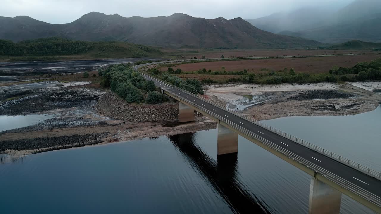 drone aéreo moviéndose hacia atrás disparado sobre el puente bradshaw que se extiende sobre el lago artificial burbury a lo largo de la costa occidental de tasmania durante la noche