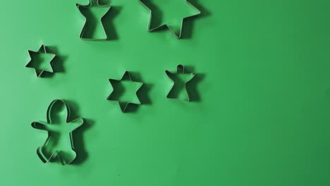 Angel,-gingerbread-man-and-star-shaped-cookie-cutters-and-copy-space-on-green-background