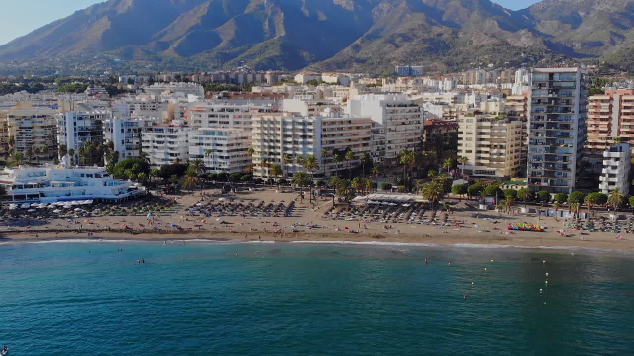 drone disparado retrocediendo sobre el agua desde la playa de marbella, españa