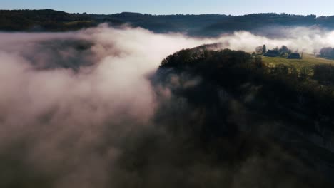 Small-house-on-the-edge-of-a-cliff,-shrouded-in-mist,-at-sunrise-in-the-Dordogne,-France