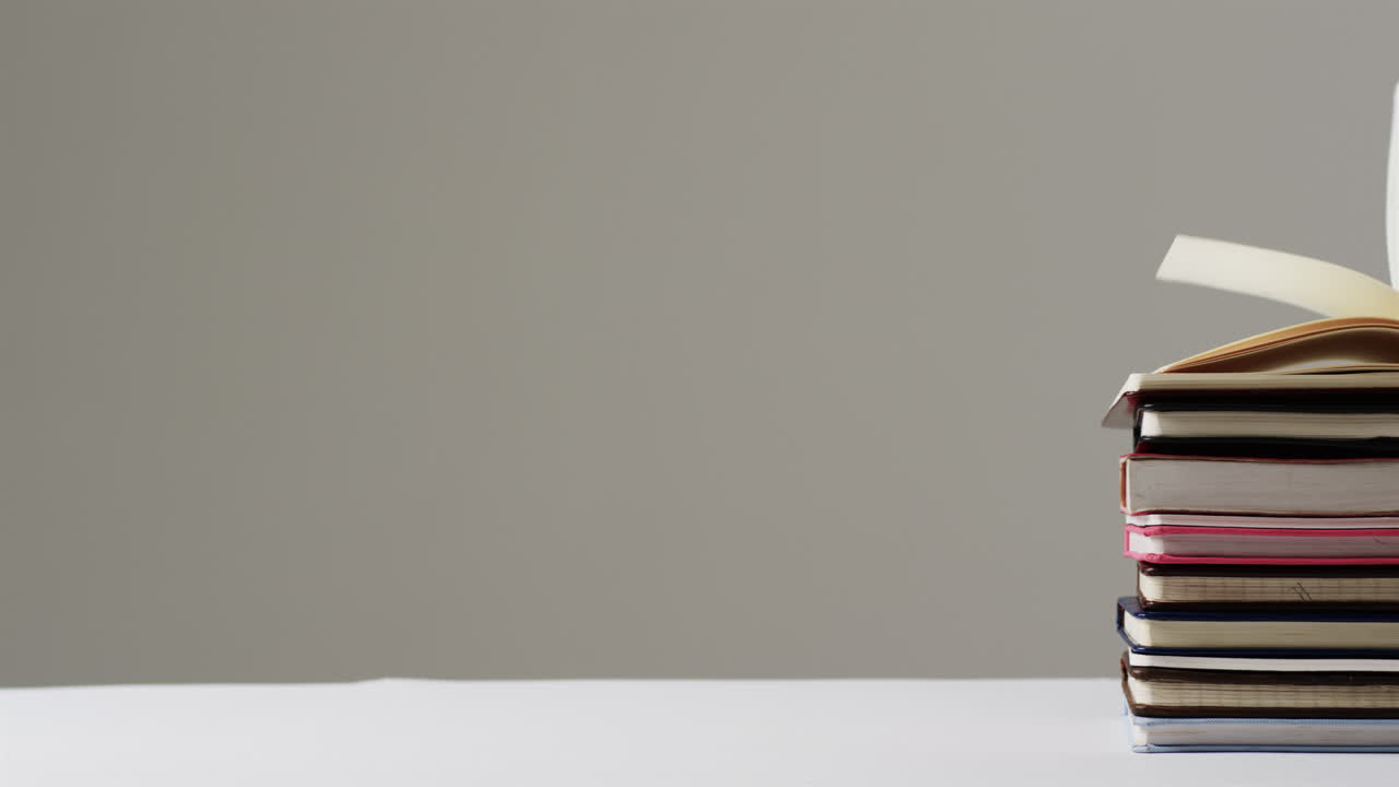 primer plano de un libro abierto en una pila de libros con espacio de copia en fondo gris, en cámara lenta