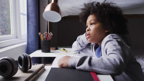 mixed race girl sitting by desk looking through window
