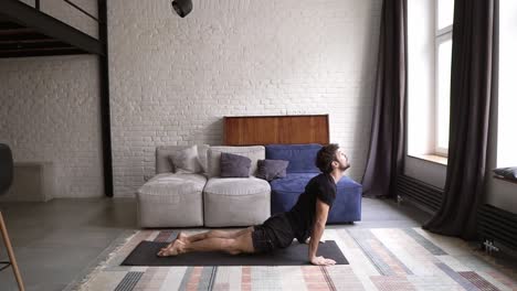 joven sano practicando yoga en el tapete, estirando la espalda