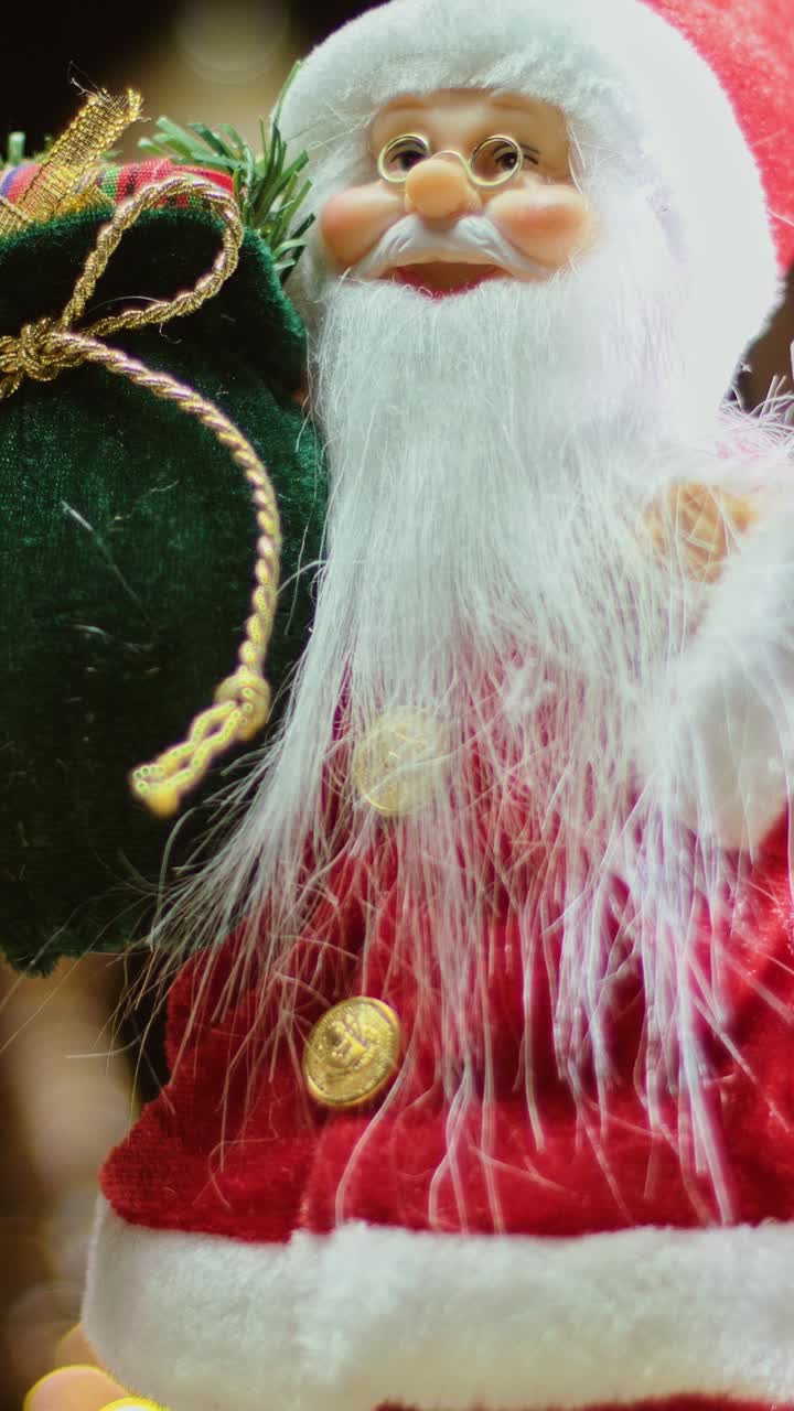 Festive Santa Claus doll with gift sack rotating in a Christmas display, vertical rotating shot