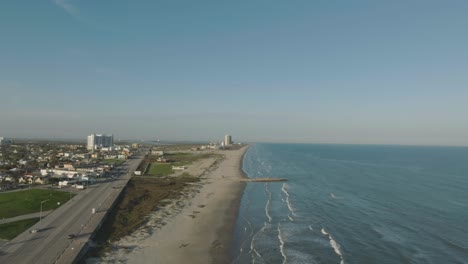 An-aerial-establishing-shot-of-the-east-end-of-Galveston-Island-along-Seawall-Blvd,-at-sunset