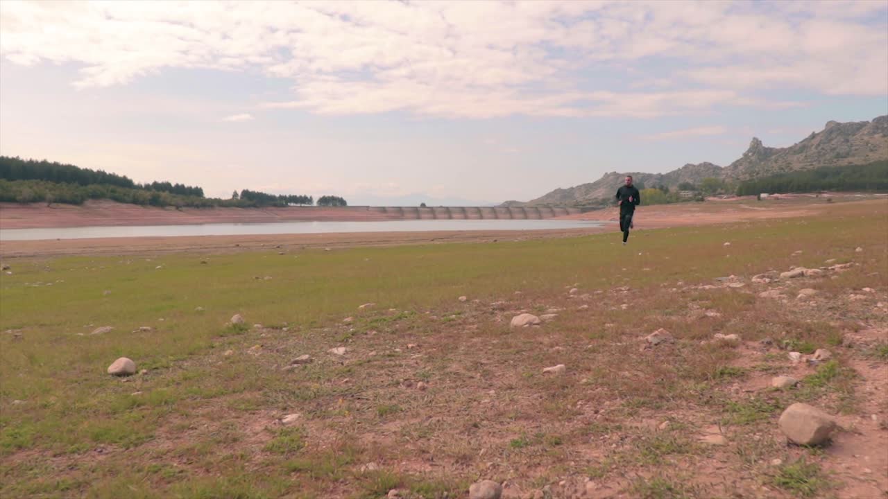 로우 앵글 샷을 움직이는 잔디 해변에서 빠르게 달리는 남자