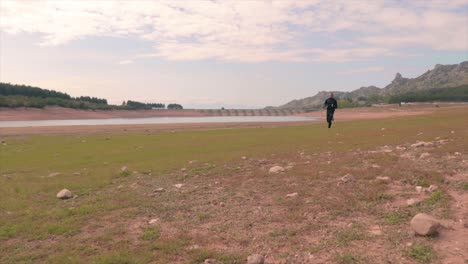 Man-running-fast-on-a-grass-beach-moving-low-angle-shot