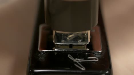 A-hand-hitting-a-black-stapler-with-no-paper-in-it-a-bunch-of-times-knocking-staples-out