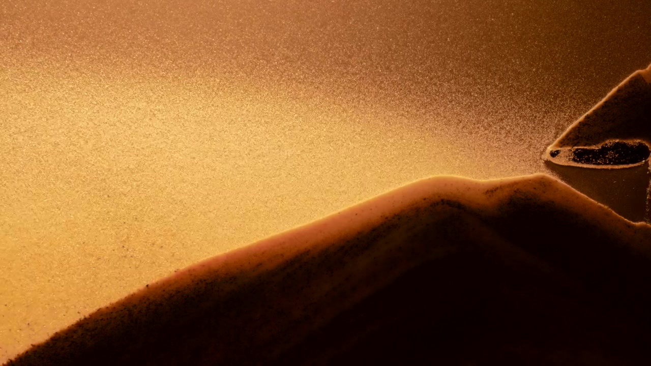 Particelle di sabbia che fluttuano intorno al mucchio di sabbia in un rallentatore astratto.
