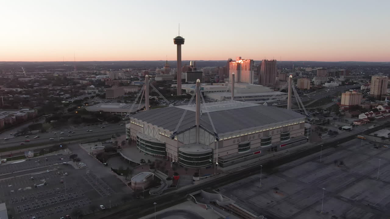 Aerial reveal of the Alamodome and Tower of the Americas in San Antonio, Texas at dusk.