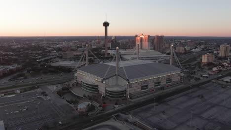 aerial reveal of the alamodome and tower of the americas in san antonio, texas at dusk.