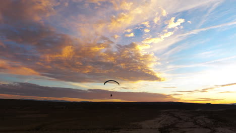 stunning sunset with the silhouette of a powered paraglider in the mojave desert