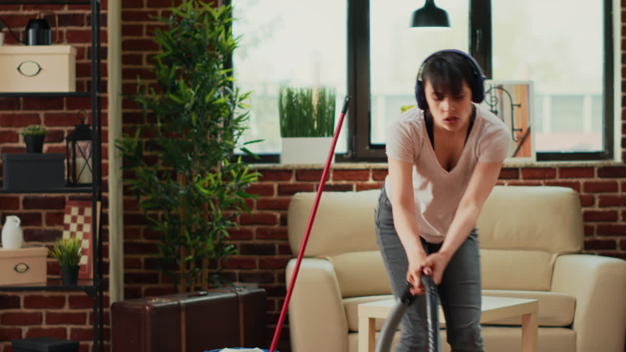 Female person listening to music on headset and vacuuming floors