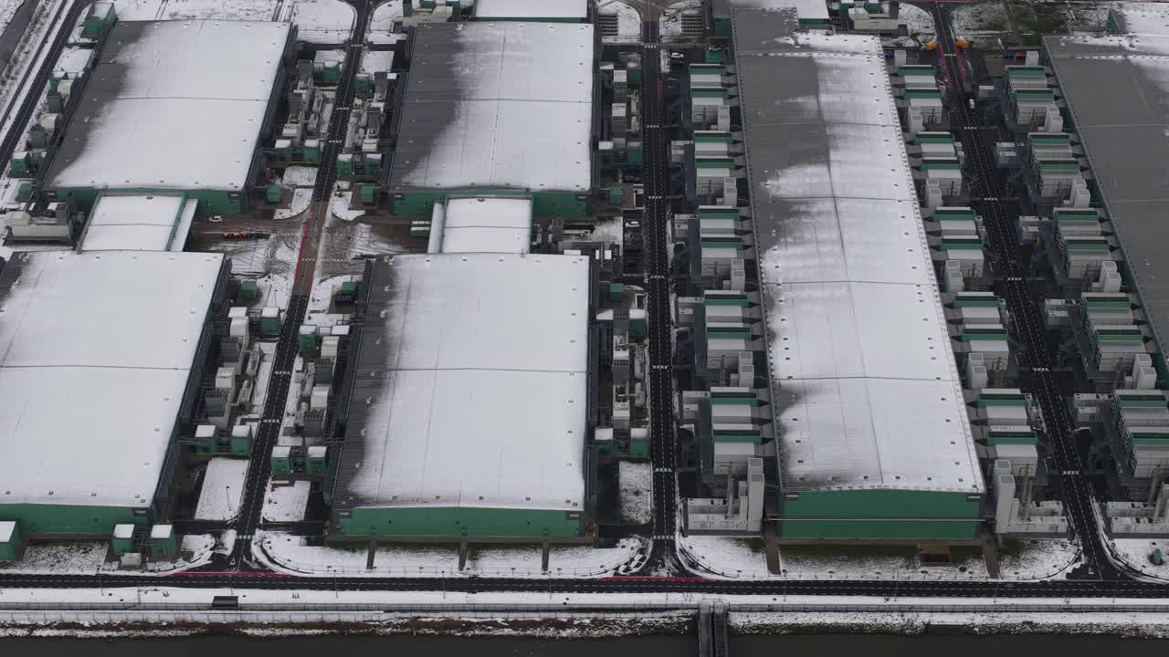 Aerial winter drone view of large data centers showing cloud computing, AI infrastructure, and massive internet technology operating at scale in a white landscape