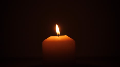 candle with its orange flame in the dark