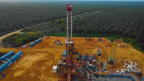 Cinematic-Drone-Footage-of-Onshore-Drilling-Rig-equipment-structure-for-oil-exploration-and-exploitation-in-the-middle-of-jungle-surrounded-by-palm-oil-trees-during-sunset-and-high-oil-price