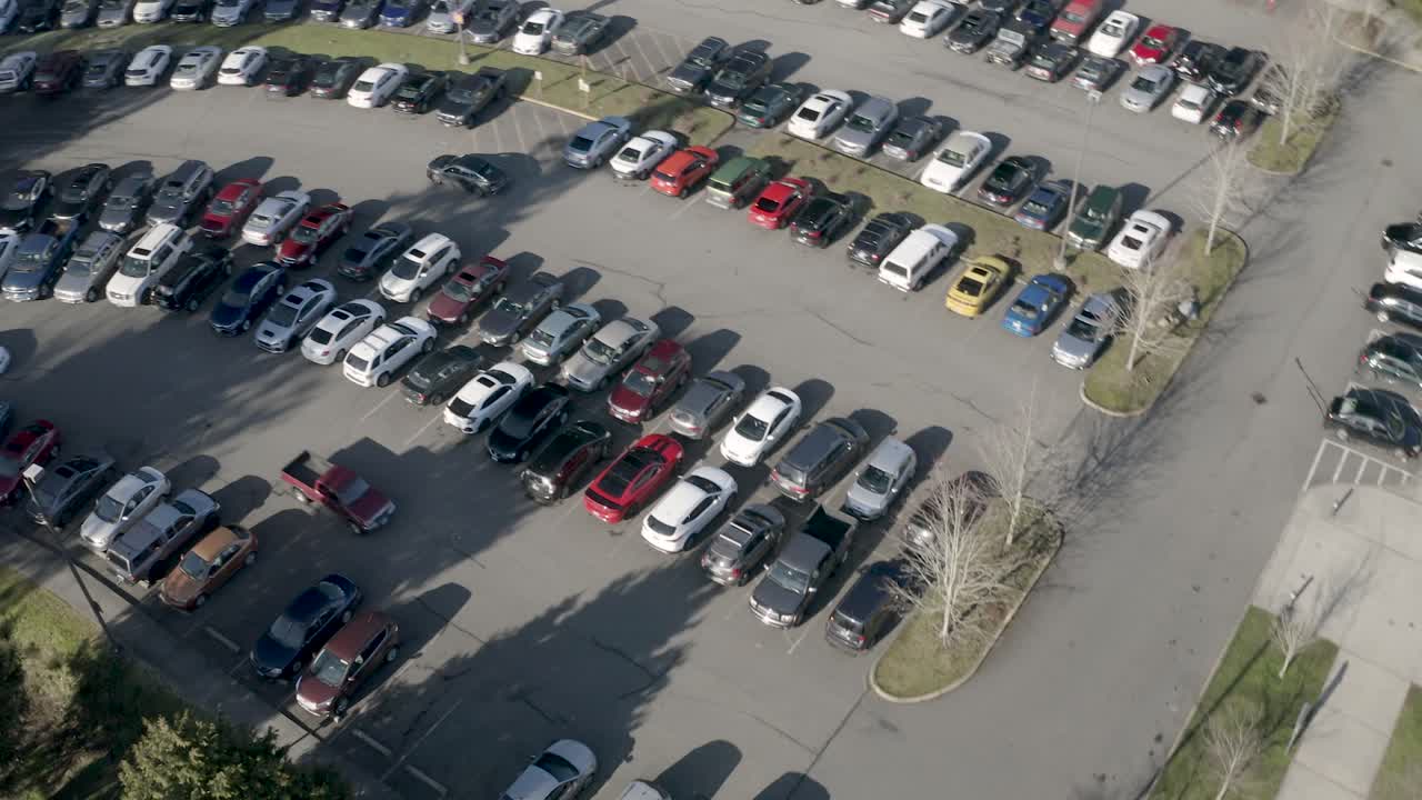Cars Driving And Searching For A Space In The Crowded Parking Lot On A Sunny Day- aerial shot