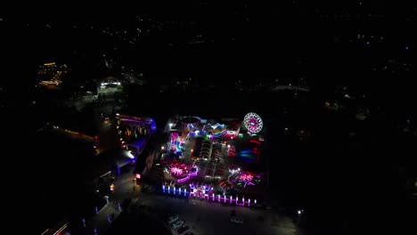 aerial pullback of nighttime pop-up carnival and amusement park with vibrant, neon lights at virac, catanduanes, philippines.