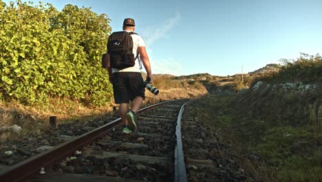 lonely photographer backpacking on endless railway track, back view