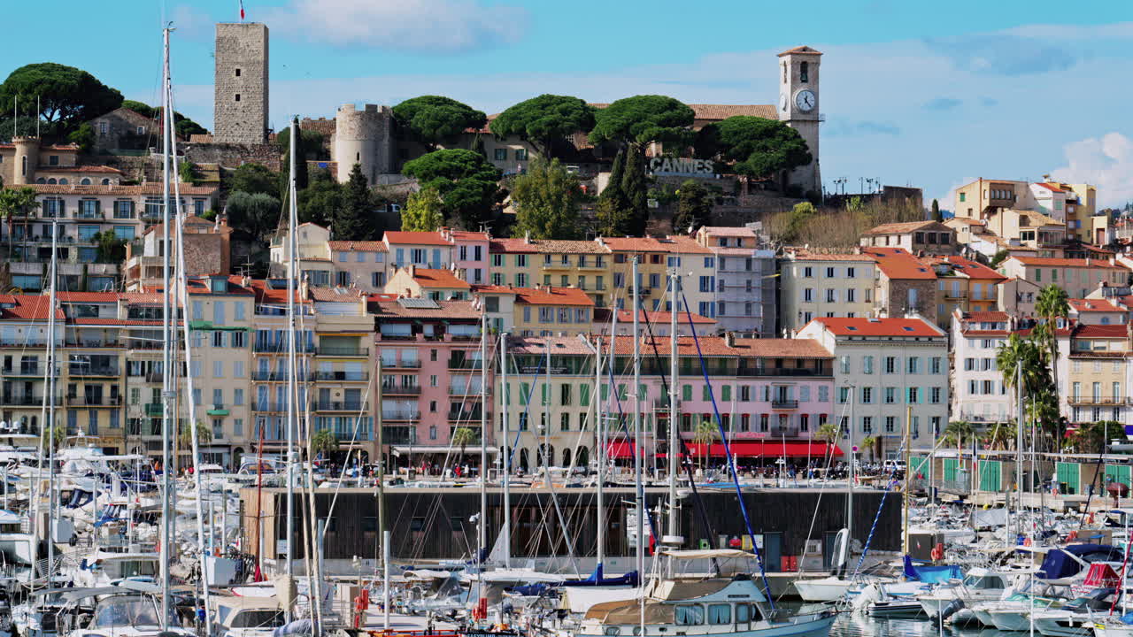 Cannes, France - February 10, 2025: Boats docked in the Cannes Marina with the colourful building of the city on the background