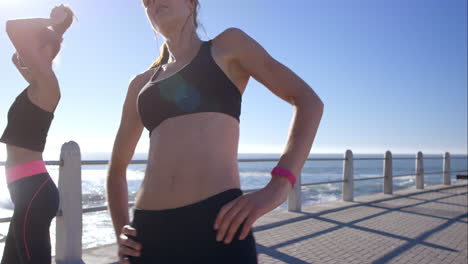 two athletic friends stretching on promenade before run