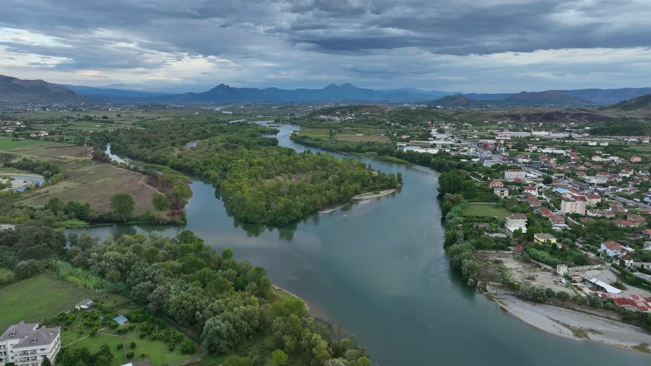 Scodra with river and lush landscape, showcasing the city and mountains, aerial view