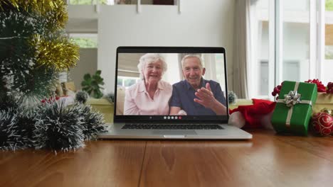 Lächelndes-Kaukasisches-älteres-Paar-Winkt-Bei-Einem-Weihnachtsvideoanruf-Auf-Dem-Laptop