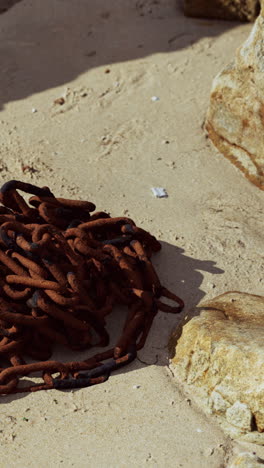 una cadena oxidada en una playa de arena