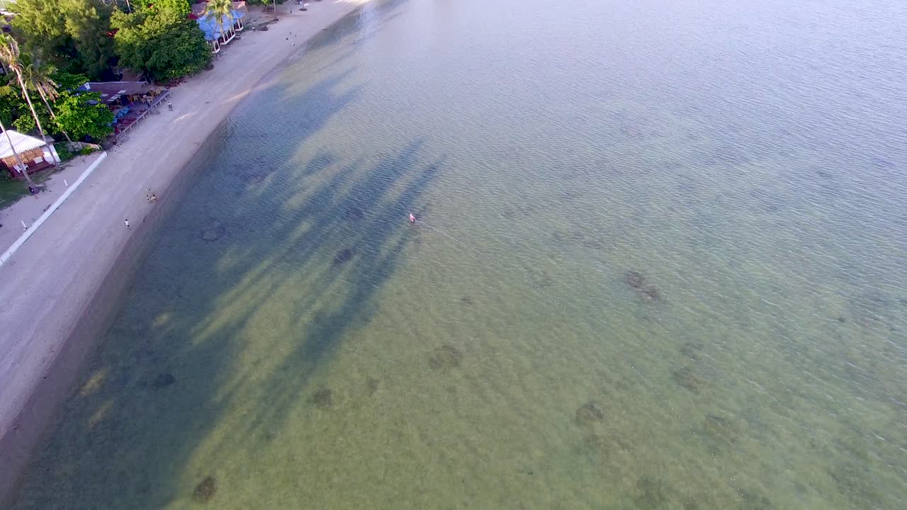 An overhead aerial drone panning of Bann Tai beach off the coast of Koh Phangan in the south of Thailand