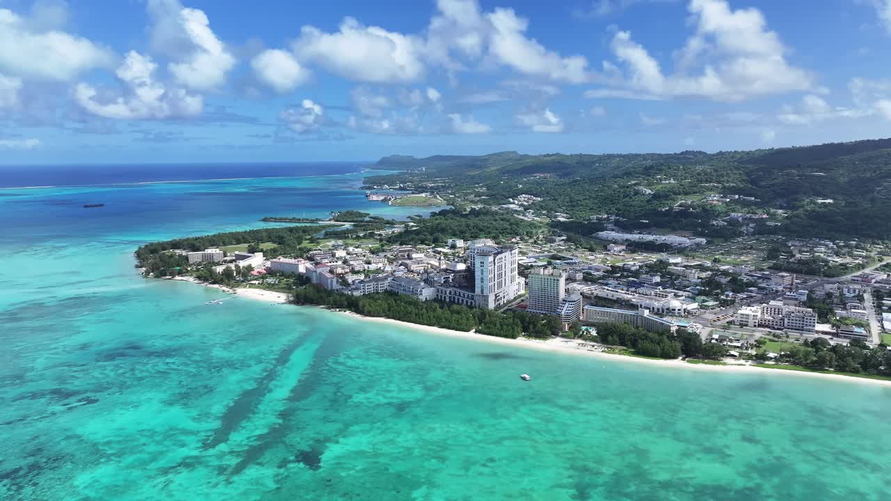 Scopri la porta d'accesso alle Isole Marianne Settentrionali. Questa vista aerea di alta qualità mostra la splendida costa occidentale di Saipan, con l'iconico skyline degli hotel di lusso di Garapan e le distese