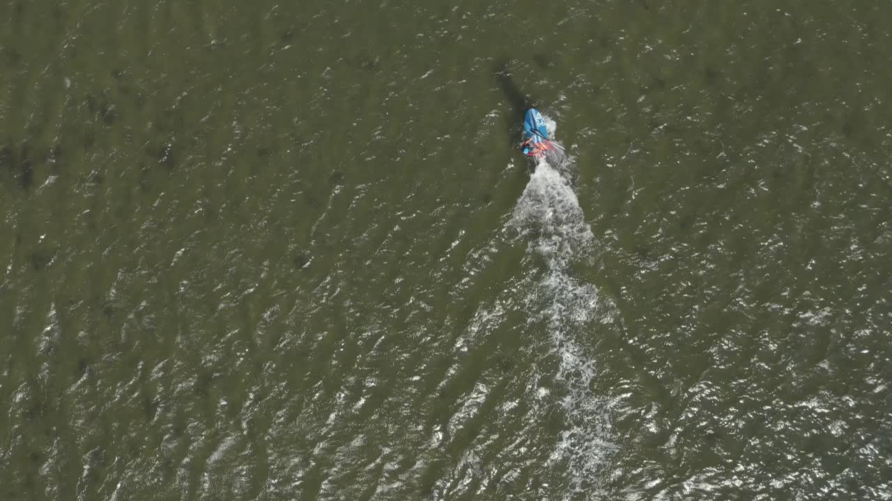 drone - toma aérea superior de un surfista en un mar azul, ondulado y ventoso en un día soleado, 30p