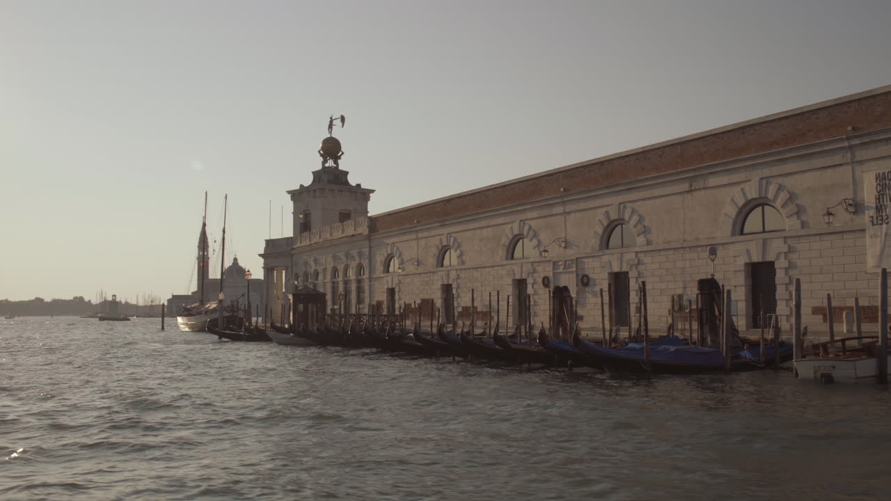 Wide shot of Gondolas in front of Punta della Dogana, Museum of art on a beautiful sunny morning, Venice, Italy