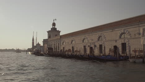 wide shot of gondolas in front of punta della dogana, museum of art on a beautiful sunny morning, venice, italy