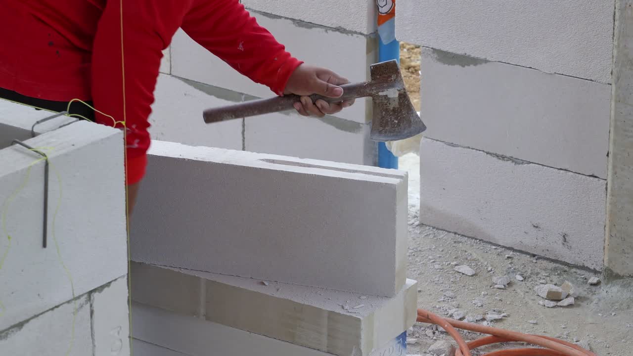 Un operaio edile martella abilmente blocchi da muro in un vivace cantiere.