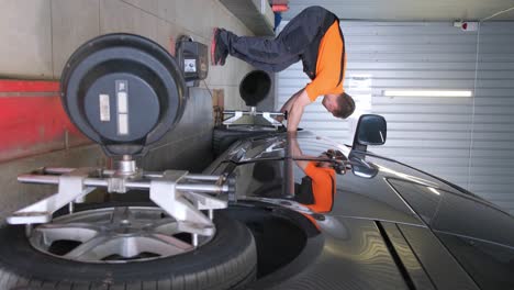 mechanic performing wheel alignment on a car in an auto service garage