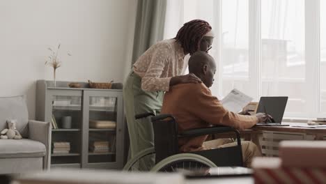 woman helping handicapped african-american man doing paperwork